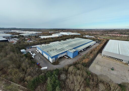 Morrisons Distribution Centre, United Kingdom - 14 February 2026: Aerial view of a vast distribution center amidst a tapestry of autumnal trees, punctuated by the stark white of parked trucks.