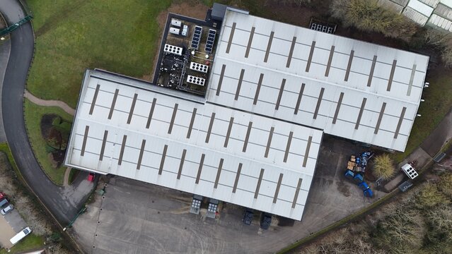Aerial view of the Node4 Data Centre, a symmetrical industrial landscape with silver roofs contrasting with the surrounding greenery, Northampton, United Kingdom.