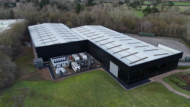 Aerial view of the Node4 Data Centre surrounded by verdant lawns and muted trees, a stark contrast to the building's dark, modern facade, Northampton, United Kingdom.