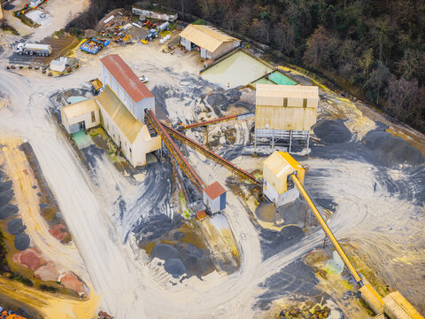 Aerial view of a quarry's industrial heart, where earth's raw materials meet human endeavor in a symphony of dust and machinery, Plouasne, Brittany, France.