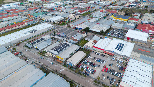 Aerial view of a sprawling industrial area with rows of warehouses, factories, and parked cars under a soft sky, Caceres, Extremadura, Spain.