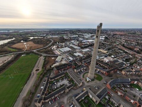 Aerial view of the monolithic National Lift Tower piercing the skyline, casting a long shadow over the urban sprawl of Northampton, United Kingdom.