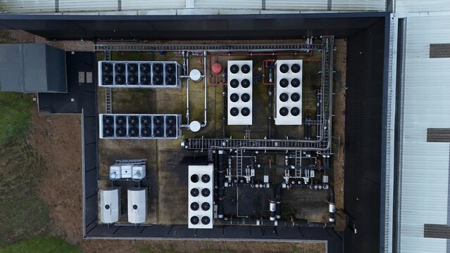 Aerial view of cooling systems on a rooftop amidst a mix of textures and industrial structures, contrasting against the urban landscape, Northampton, United Kingdom.