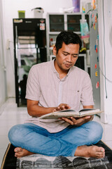 Man Reading Holy Book While Sitting on Prayer Mat