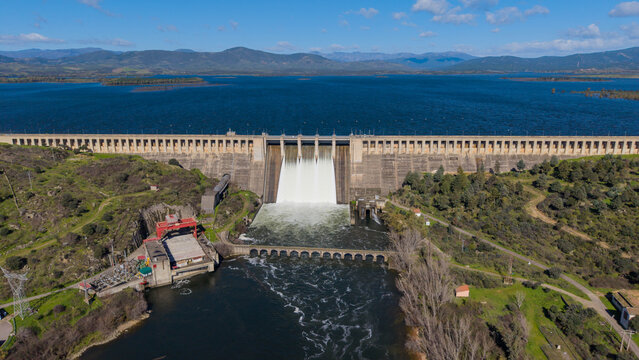 Aerial view of the majestic dam holding back the vast, deep blue reservoir, framed by rolling hills, a symphony of concrete and nature's grandeur, Caceres, Caceres, Espana.