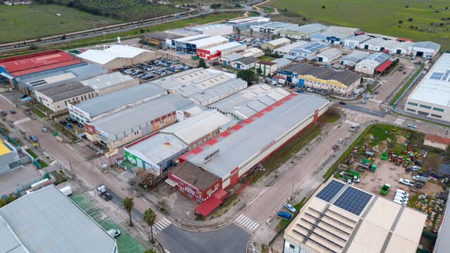 Aerial view of a sprawling industrial park, with buildings of various sizes and colors contrasting against the green landscape, Caceres, Extremadura, Spain.