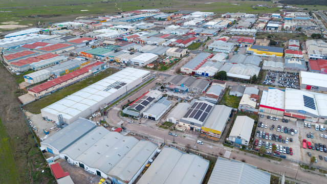 Aerial view of a sprawling industrial park reveals a tapestry of rooftops under a vast sky, reflecting the blend of commerce and landscape, Caceres, Extremadura, Spain.