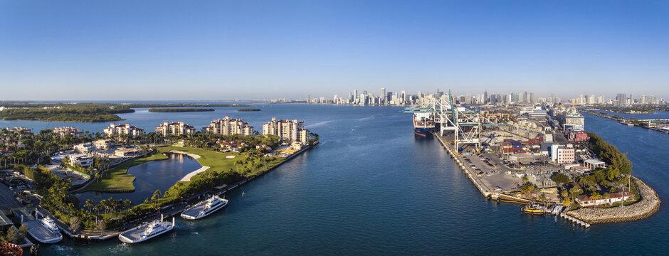 Miami, USA - 07 February 2026: Aerial view of Fisher Island's opulent residences meet the bustling Port Miami, where cargo ships stand against the city skyline.
