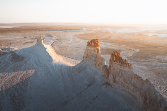 Aerial view of chalk cliffs and vast desert landscape bathed in the soft, warm light of the setting sun, Aktau, Mangystau Region, Kazakhstan.