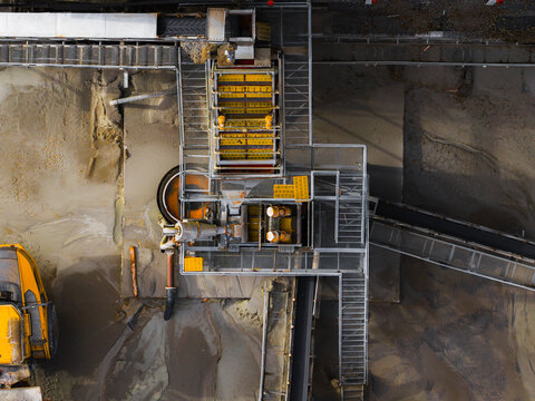 Aerial view of heavy machinery amidst piles of sand and gravel, creating a stark industrial landscape, Gourlizon, Brittany, France.