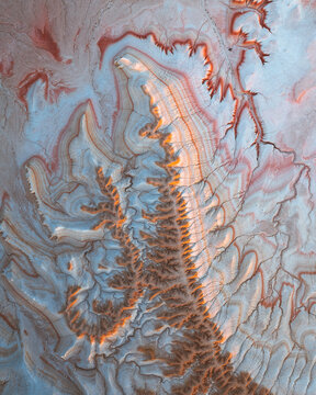 Aerial view of rugged, multi-hued terrain with warm highlights and cool shadows creating a dramatic landscape, Kyzylkum, Mangystau Region, Kazakhstan.