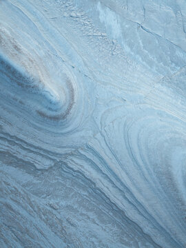 Aerial view of the ethereal, swirling patterns etched into the earth like brushstrokes of pale blue and silver, creating a mesmerizing abstract landscape, Aktau, Mangystau Region, Kazakhstan.