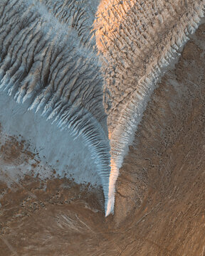 Aerial view of wind-swept ridges casting long shadows across the stark, textured landscape, creating a mesmerizing contrast of light and dark, Aktau, Mangystau Region, Kazakhstan.