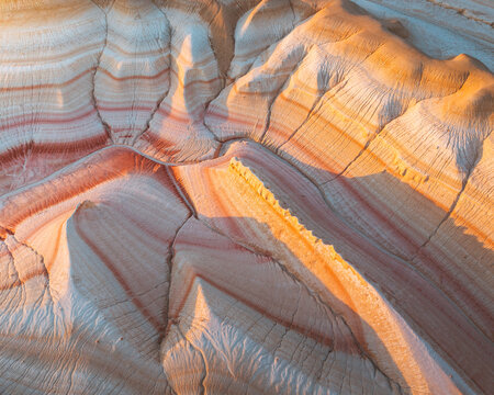 Aerial view of the striated cliffs painted in earthy tones of beige, orange, and red, sculpted by wind and time, creating a mesmerizing landscape, Kyzylkum, Mangystau Region, Kazakhstan.