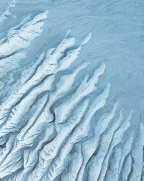 Aerial view of the stark, textured earth reveals a landscape of pale ridges and shadows, a study in contrasts and subtle gradients, Mangystau Region, Kazakhstan.