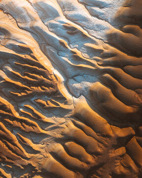 Aerial view of golden dunes sculpted by wind and time create mesmerizing patterns in the desert landscape, Kyzylkum, Mangystau Region, Kazakhstan.