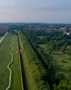 Aerial view of the ancient city walls contrasting with modern green spaces and sinuous pathways, a blend of history and nature, Ferrara, Emilia-Romagna, Italy.