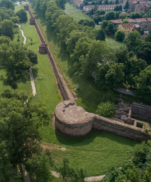 Aerial view of ancient walls snaking through a verdant landscape where the weathered stone battles the persistent green, Ferrara, Emilia-Romagna, Italy.