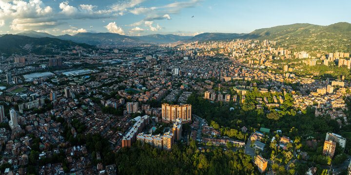 Aerial view of the city sprawling across the valley floor, embraced by verdant mountains under a vast sky, Medellin, Antioquia, Colombia.