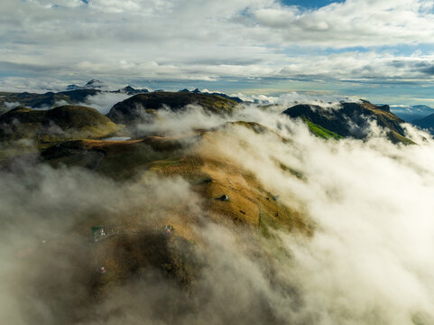 Aerial view of clouds dancing through the hills and mountains, where the earth's rugged textures meet the sky's soft embrace, Manizales, Caldas, Colombia.