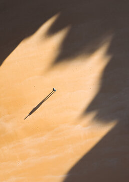 Aerial view of a lone figure casts a long shadow on the beach, the sun creating dramatic contrasts, Alvor, Faro, Portugal.