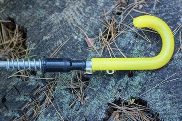 one yellow plastic handle on an umbrella on the street on a gray table