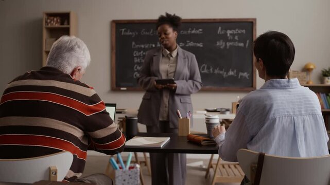 African American female teacher and senior student engaging in interactive discussion during classroom lesson with active participation and learning