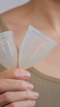 Education Female Health, Menstruation, Periods. White Woman Comparing Two Menstrual Cup Sizes Closeup Hands Holding Small And Large Models, Guidance On Fit And Volume For Different Bodies, Informative