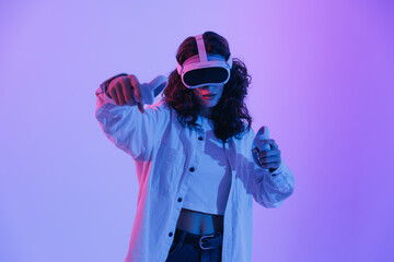 Young asian female engaged in vr gaming with headset in vibrant neon lighting with two controllers © Parilov