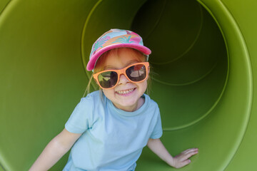 Girl having fun in tube slide on playground