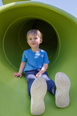 Boy having fun in tube slide on playground