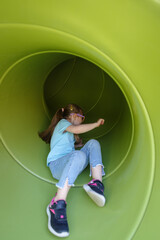 Girl having fun in tube slide on playground