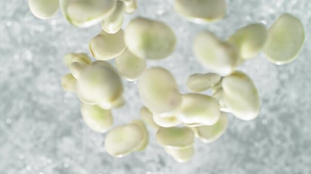 Broad Beans Falling Into Pot Of Boiling Water Making A Splash In Slow Motion, Table Top View