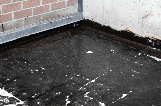 Patio waterproofing with liquid membrane. Fluid applied liquid coating on concrete floor with vertical upturn detail. Exterior leak repair on balcony, patio or foundation. Selective focus.