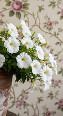 Elegant White Flowers in Vase Against Floral Wallpaper Backdrop.