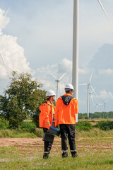 Engineer team standing near wind turbine carrying maintenance equipment reviewing renewable energy task promoting sustainable electric generation teamwork innovation outdoor green technology project © Ekkasit A Siam
