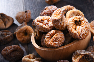 Composition with bowl of dried figs on wooden table