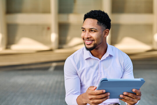 Portrait of a young  businessman wman using a tablet computer  in a city park, surrounded by modern corporate office buildings architecture