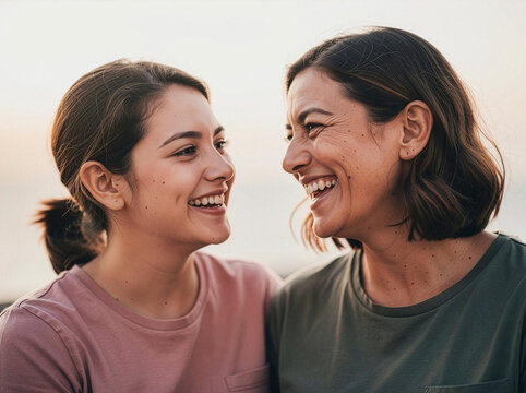 Dos personas compartiendo una sonrisa espont&aacute;nea, luz natural suave, fondo simple