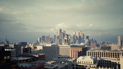 Fototapeta premium city skyline at soft evening light, vintage cinematic panorama of downtown rooftops and distant skyscrapers under moody clouds, warm highlights and muted tones,