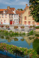 Obraz premium Medieval flemish architecture, houses reflecting in a canal, Bruges colorful cityscape with flowers in summer, Belgium