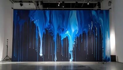 A large, abstract, blue-dripped artwork on black, in an empty space