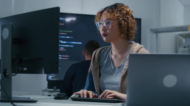 Concentrated Asian AI Programmer and Machine Learning Developer Focused on Screen, Writing code, Working on website development, software developing project in software company office.