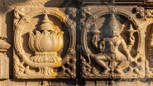 Ancient Stone Carvings Of Lotus Flower And Deity On Textured Wall In Sunlight