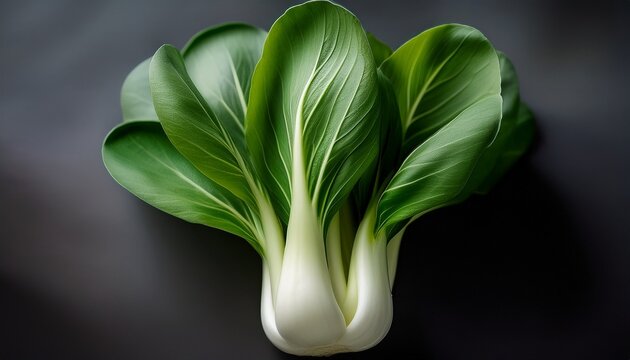close up of a bok choy head vibrant green leaves tightly clustered around a pale creamy white stem fresh crisp appearance