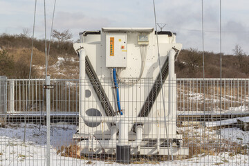 Kontenerowa instalacja techniczna z wentylatorami i szafą sterowniczą za ogrodzeniem – infrastruktura przemysłowa zimą. © Henryk Guziak