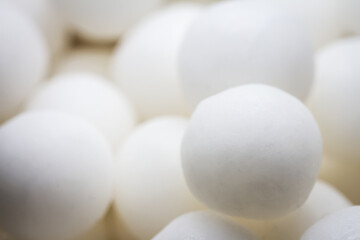 Extreme close up of white small peppermint candy balls. Selective soft focus, shallow depth of field.