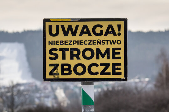 Znak ostrzegawczy &bdquo;Uwaga! Niebezpieczeństwo strome zbocze&rdquo; na tle g&oacute;r &ndash; ryzyko upadku i bezpieczeństwo na szlaku.
