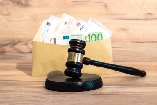 A judge's gavel in front of an envelope with euro banknotes. A legal fine, a settlement agreement, or a concept of financial punishment. Corruption in legislation and court decisions