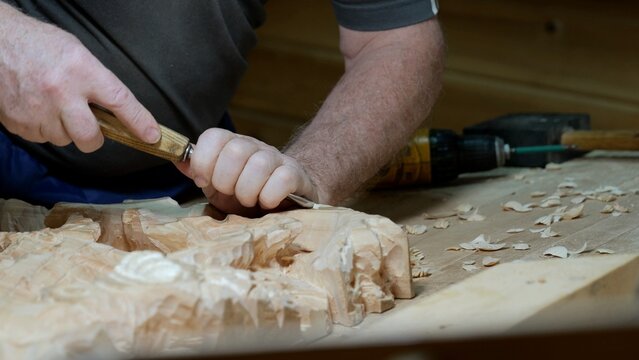 Artisan carves pattern, Master woodworker skillfully creates elegant motifs using precise tools, Seasoned craftsman delicately forms ornate decorative patterns in wood with steady strikes